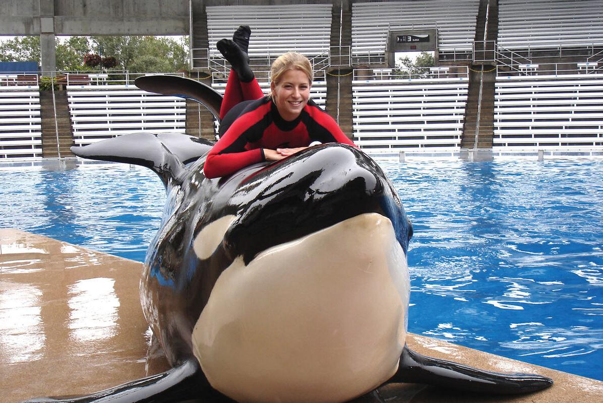 A student lays on top of an orca she worked with as part of an internship